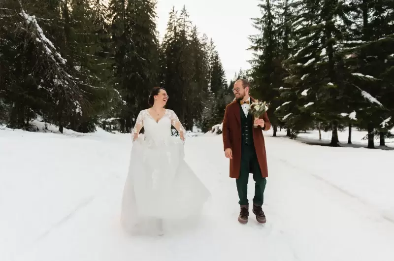 Elopement en hiver au Domaine du Baron au lac de Montriond, le couple marche dans la neige
