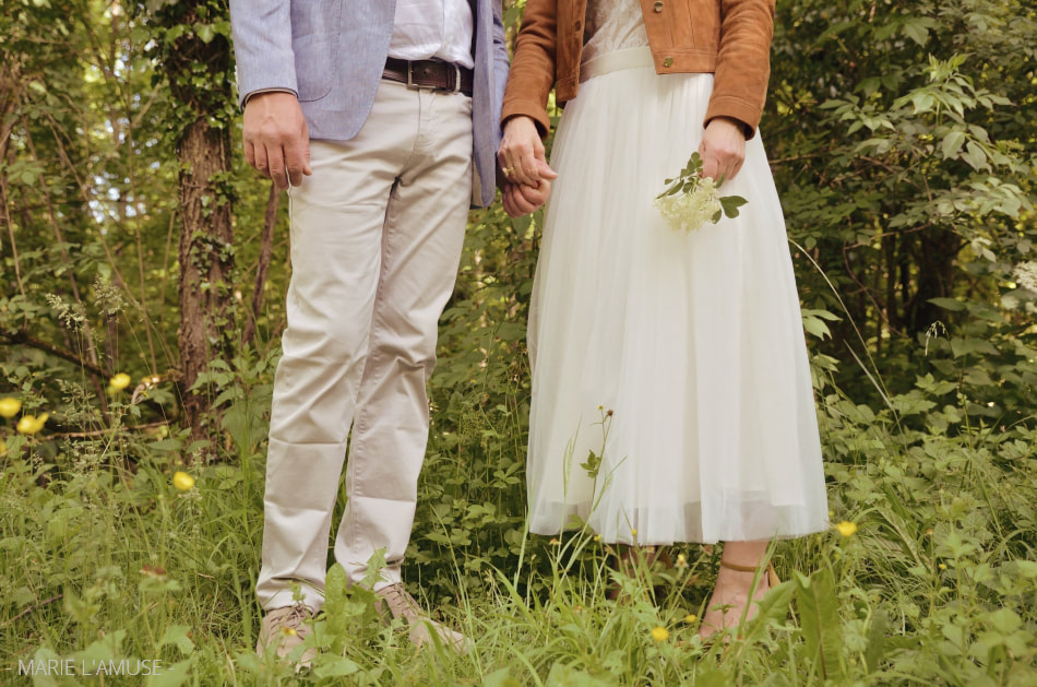 Idée d'élopement ou de petit mariage : juste à deux avec un bouquet de fleurs sauvages. Photo des pieds des mariés dans l'herbe par Marie l'Amuse photographe