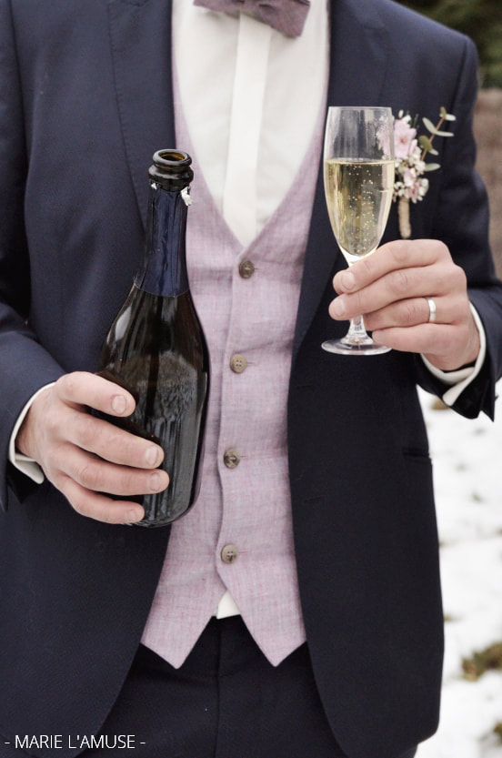 Idée d'élopement ou mariage intime : la marié débouche le champagne en hiver par Marie l'Amuse photographe