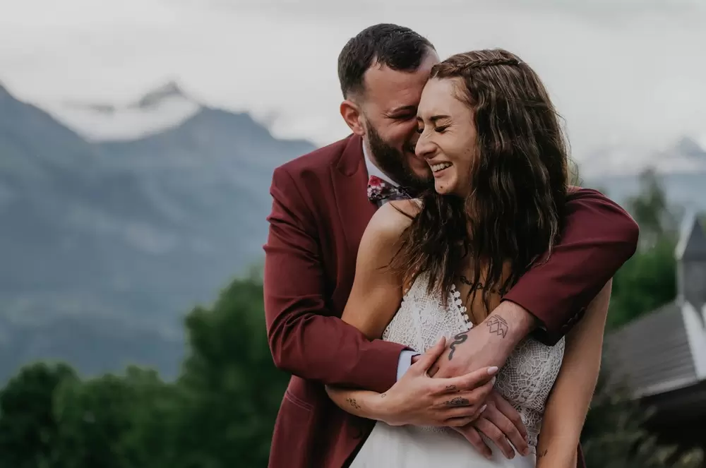Elopement devant le Mont-Blanc dans les Alpes, les mariés partagent un moment de rires et de complicité sous la pluie