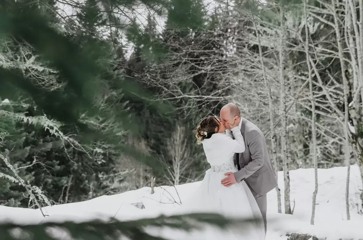 Mariage à Cordon, dans la neige et les sapins un couple s'embrasse en forêt près du Mont-Blanc