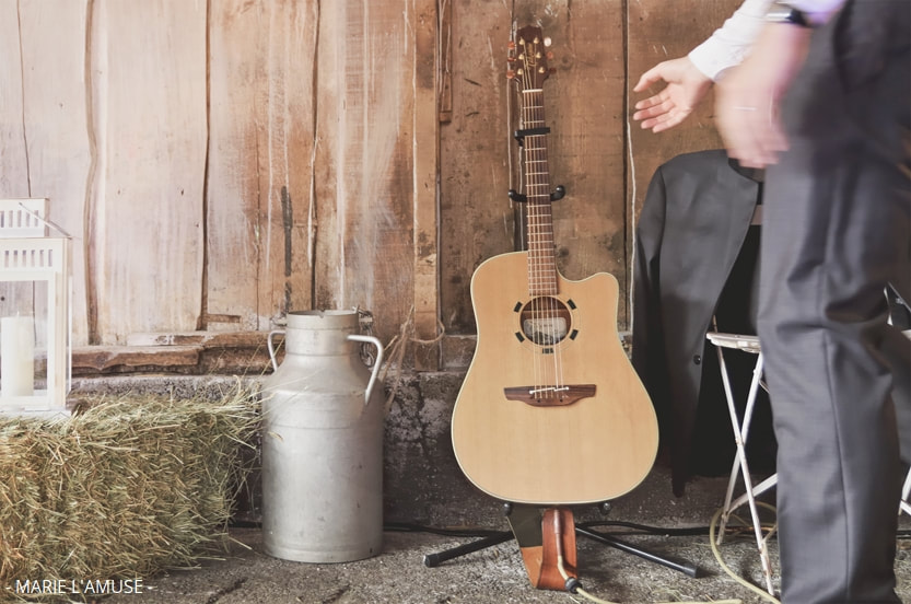 Mariage, Cérémonie, Un guitariste attrape son instrument lors de la célébration laïque dans une grange à foin, Evian Haute Savoie 2018, Photographe Marie l'Amuse