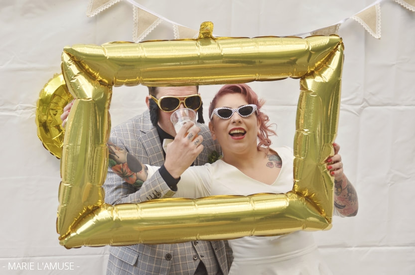 Mariage, Photobooth, Le couple est déguisé derrière un cadre gonflable doré, Marignier Haute Savoie 2019, Photographe Marie l'Amuse
