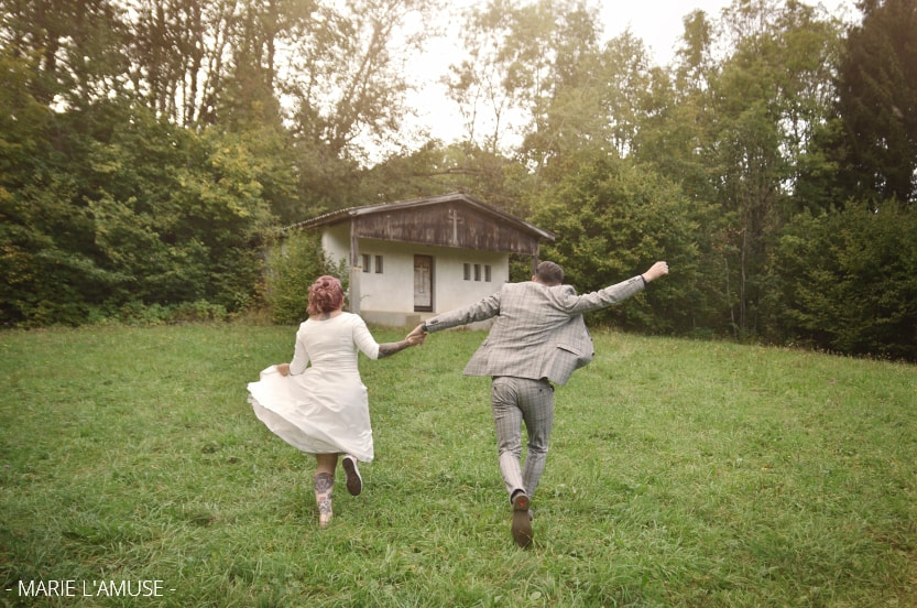 Mariage, Couple, Les mariés courent dans les champs en direction de la chapelle, Marignier Haute Savoie 2019, Photographe Marie l'Amuse
