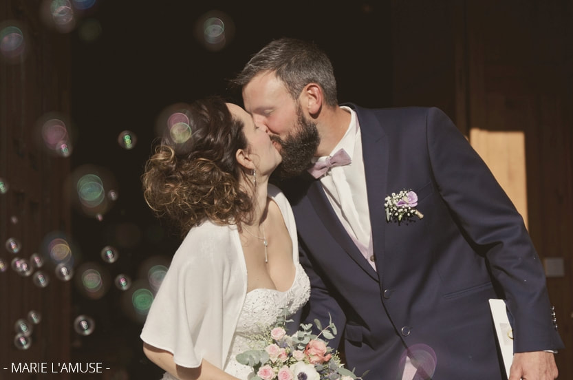 Mariage, Cérémonie, Les mariés s'embrassent sur les marches de l'église avec des bulles, Vailly Haute Savoie -2019, Photographe Marie l'Amuse

