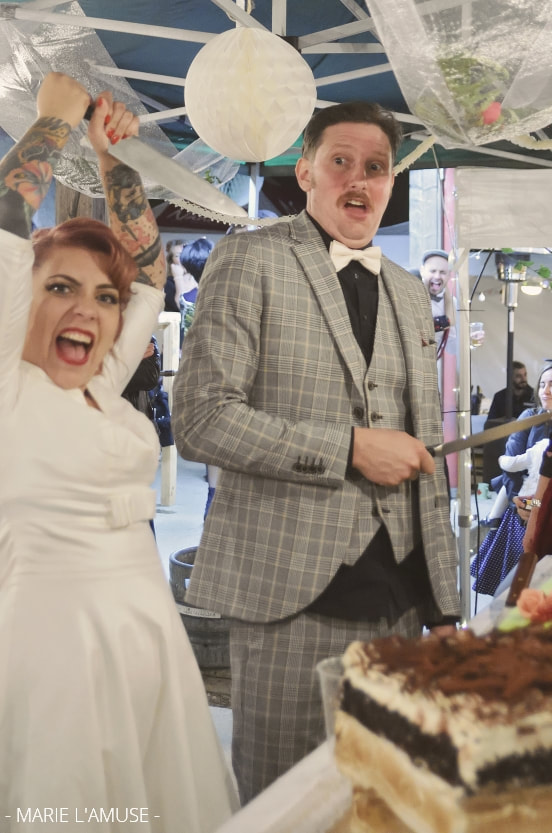Mariage, Soirée, La mariée attaque le gâteau avec son couteau, le marié est surpris, Marignier Haute Savoie 2019, Photographe Marie l'Amuse
