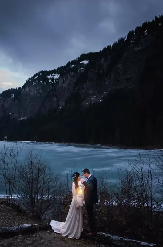 Elopement pendant la blue hour avec une lanterne devant un lac gelé en Haute-Savoie en hiver
