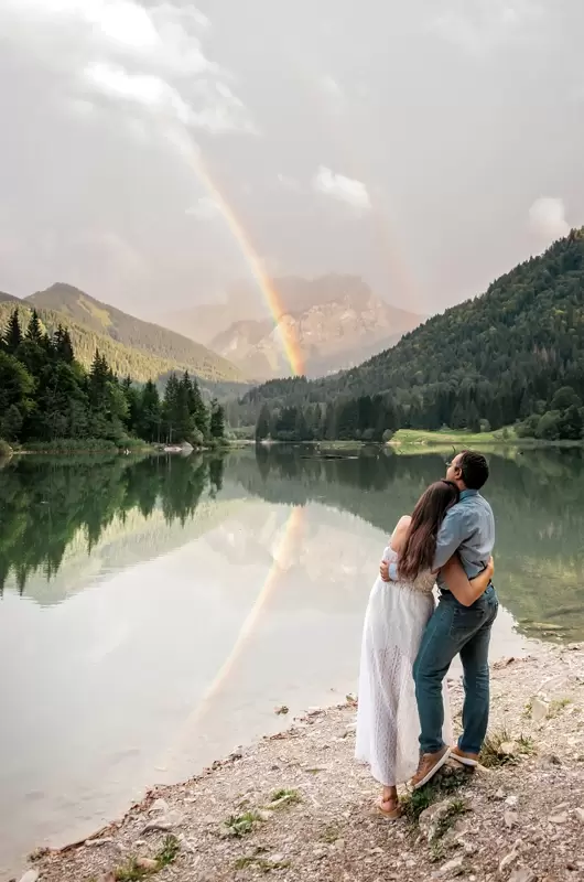 Un couple admire un arc-en-ciel lors d'un mariage intime au bord d'un lac de Haute-Savoie en France