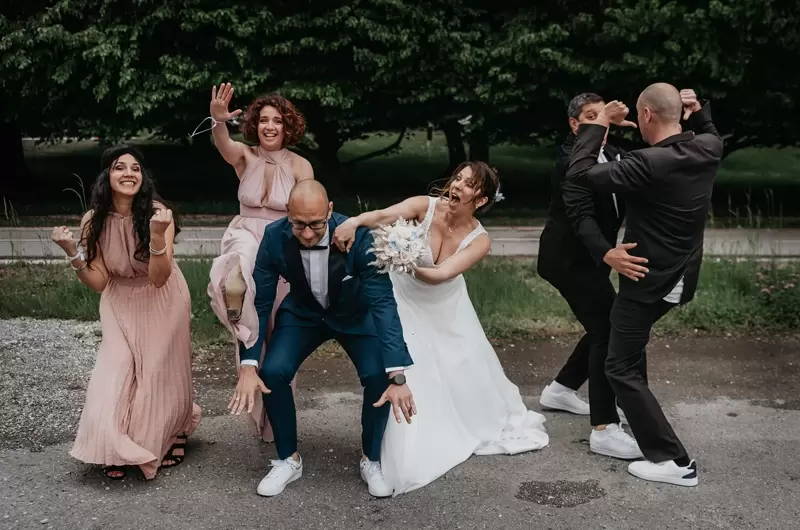 Les mariés et leurs témoins sont dans une situation drôle et originale lors des photos de groupes d'un mariage intime au lac d'Annecy