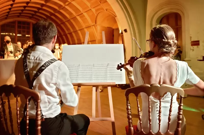 Moment original pour le couple de jeunes mariés qui interprètent un morceau au violon lors de leur mariage intime au Château de Ripaille au Lac Léman
