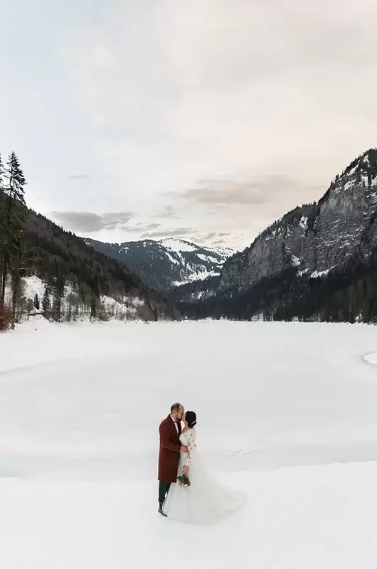 Le jour de leur mariage en hiver, le couple s'embrasse sur les rives du lac gelé à Montriond dans les Alpes