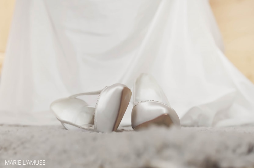 Préparatifs : gros plan sur les chaussures de mariée en satin blanc. Mariage Bellevaux, Haute-Savoie.