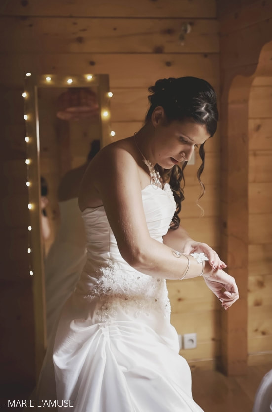 Préparatifs : la mariée enfile son bracelet en métal ouvragé et fleurs banches. Mariage Bellevaux, Haute-Savoie.