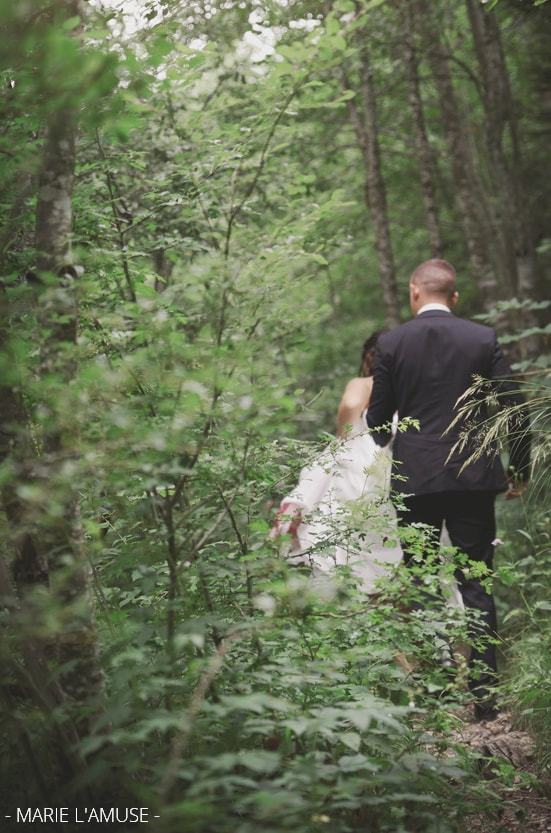 Séance photo de couple : les mariés marchent dans la forêt, zoom sur les plantes. Mariage, lac de Vallon, Bellevaux, Haute-Savoie.