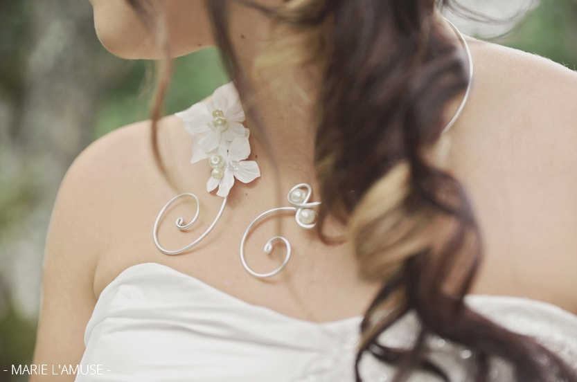 Gros plan sur le collier de la mariée, en métal ouvragé et fleurs blanches. Mariage Bellevaux, Haute-Savoie.
