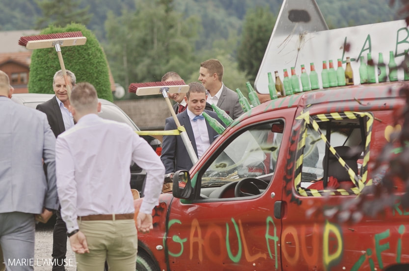 Les invités regardent la voiture balai rouge décorée avec des bières. Mariage Bellevaux, Haute-Savoie.