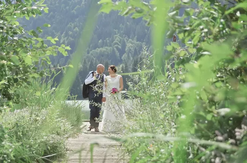 Mariage, rires des mariés sur le ponton entre les roseaux du lac de Vallon en Haute-Savoie
