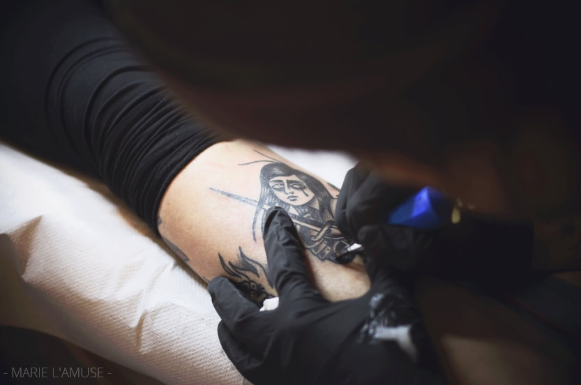 Reportage professionnel, entreprise, Grim Antihero de Noir Tattoo Fribourg tatoue un client, France, Photographe Marie l'Amuse
